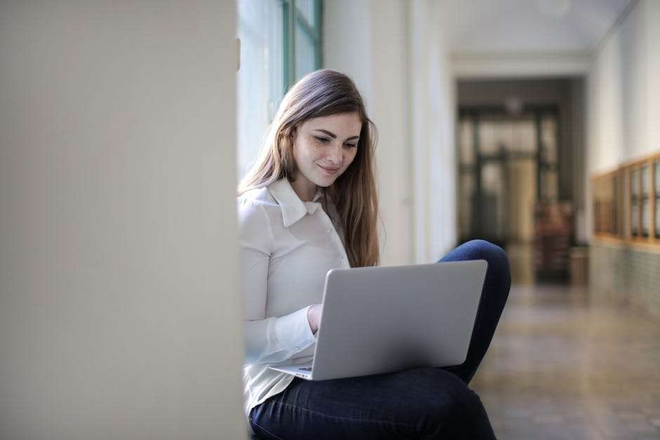 Smiling woman using a laptop indoors, representing modern remote education.