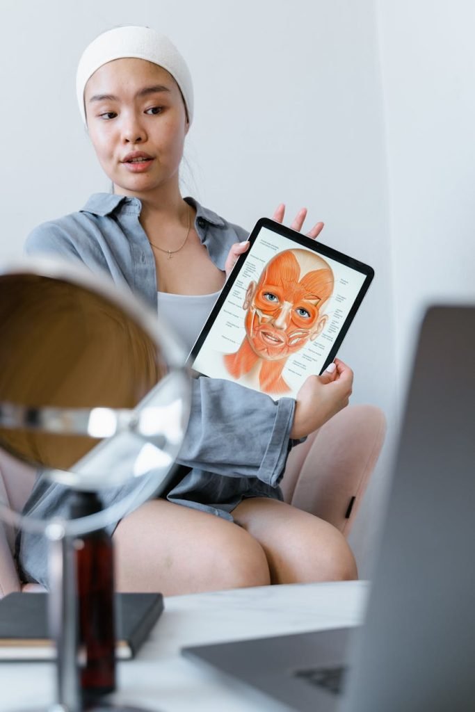 Young woman explaining skin care using an anatomy chart on a tablet during a therapy session.